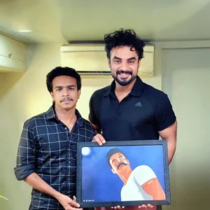 Adhil Noushad presenting his artwork to Malayalam actor Tovino Thomas, recognized as the best graphic designer in Kerala